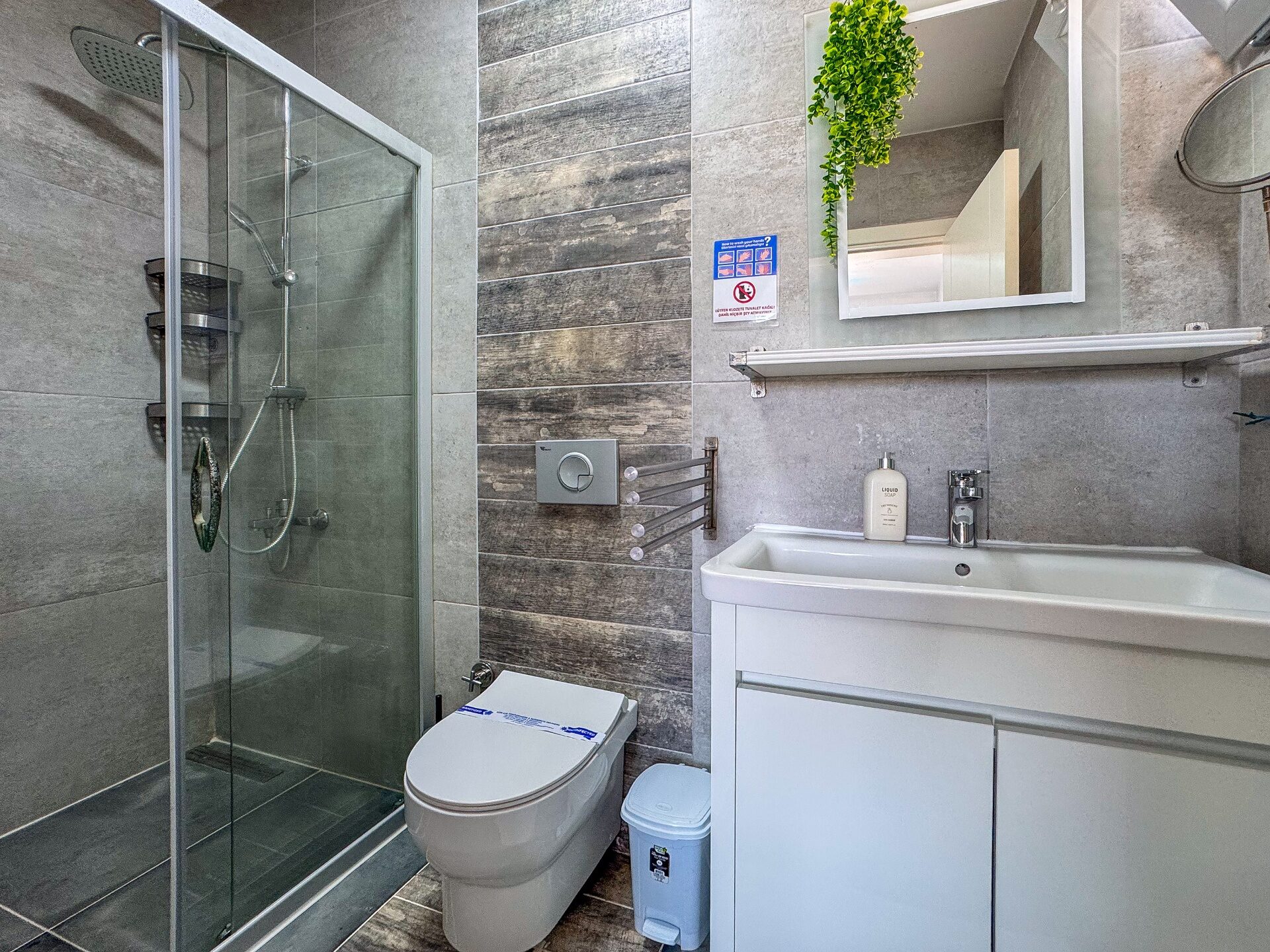 Second bathroom with grey wood-effect tiles, glass shower enclosure and vanity