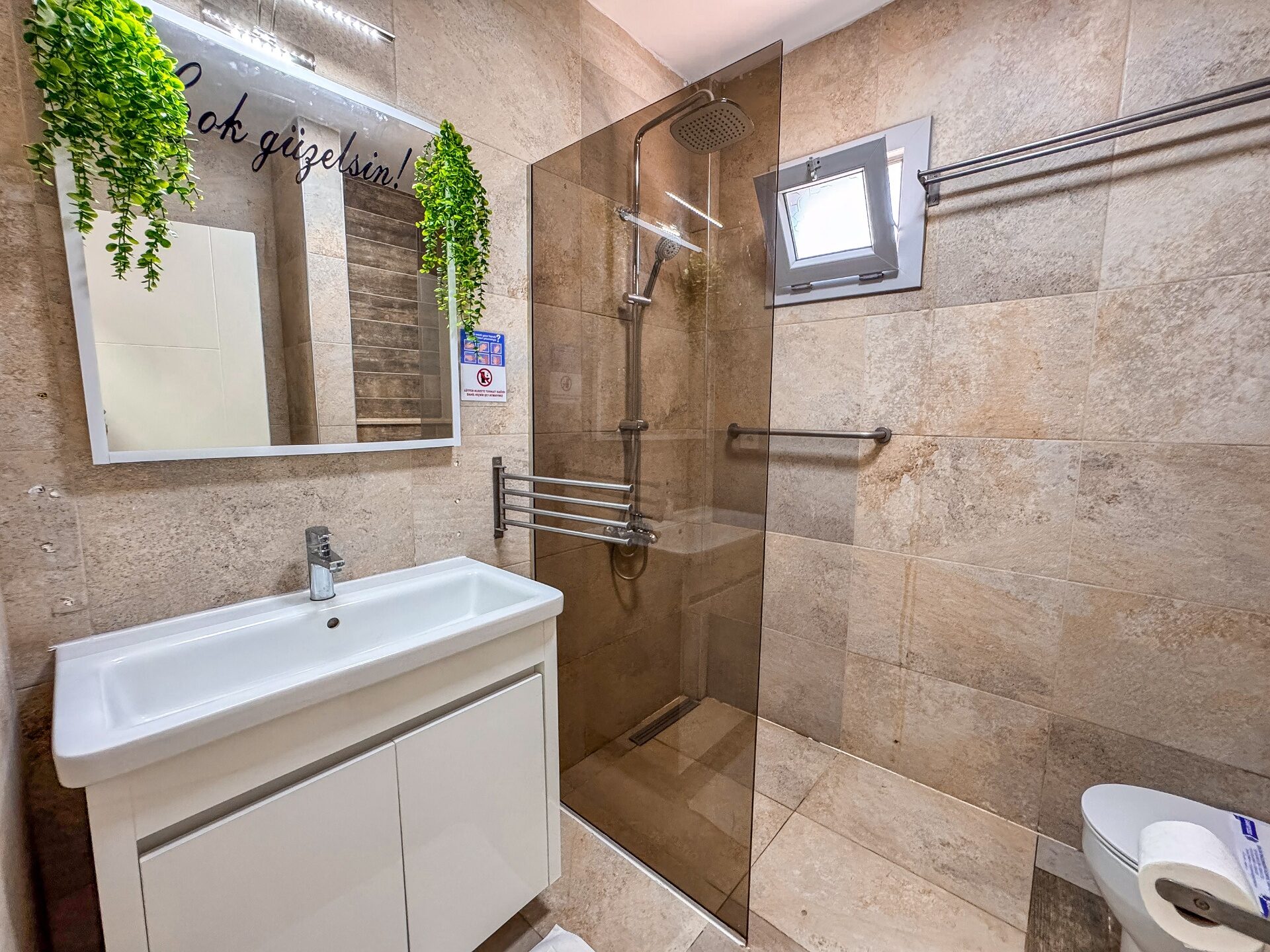 Main bathroom with warm stone tiles, walk-in shower and vanity