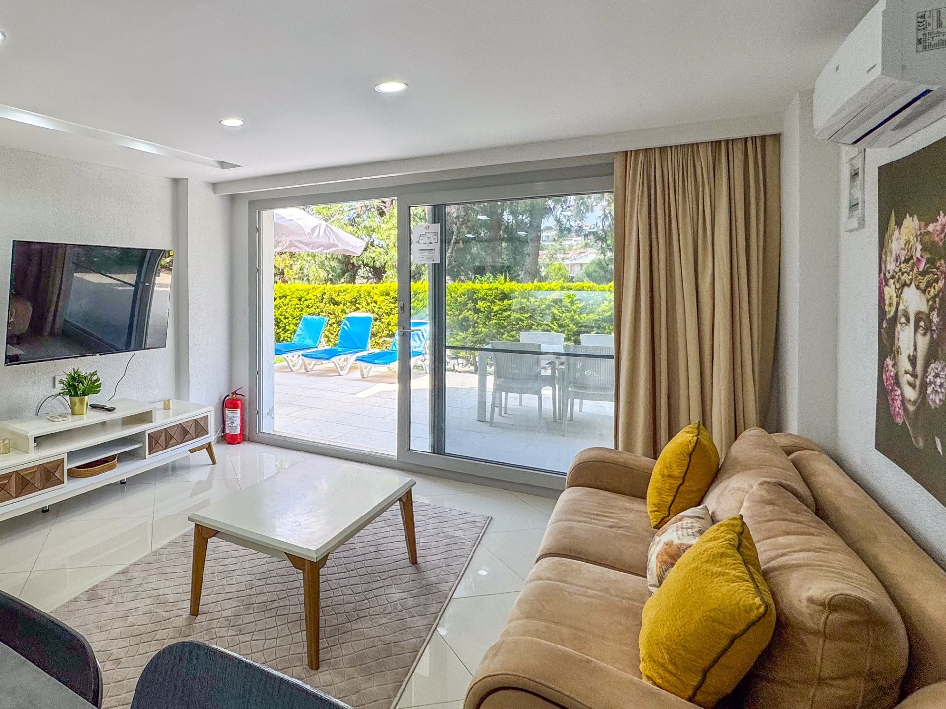 Bright living room with sliding glass doors opening to the private garden patio and loungers