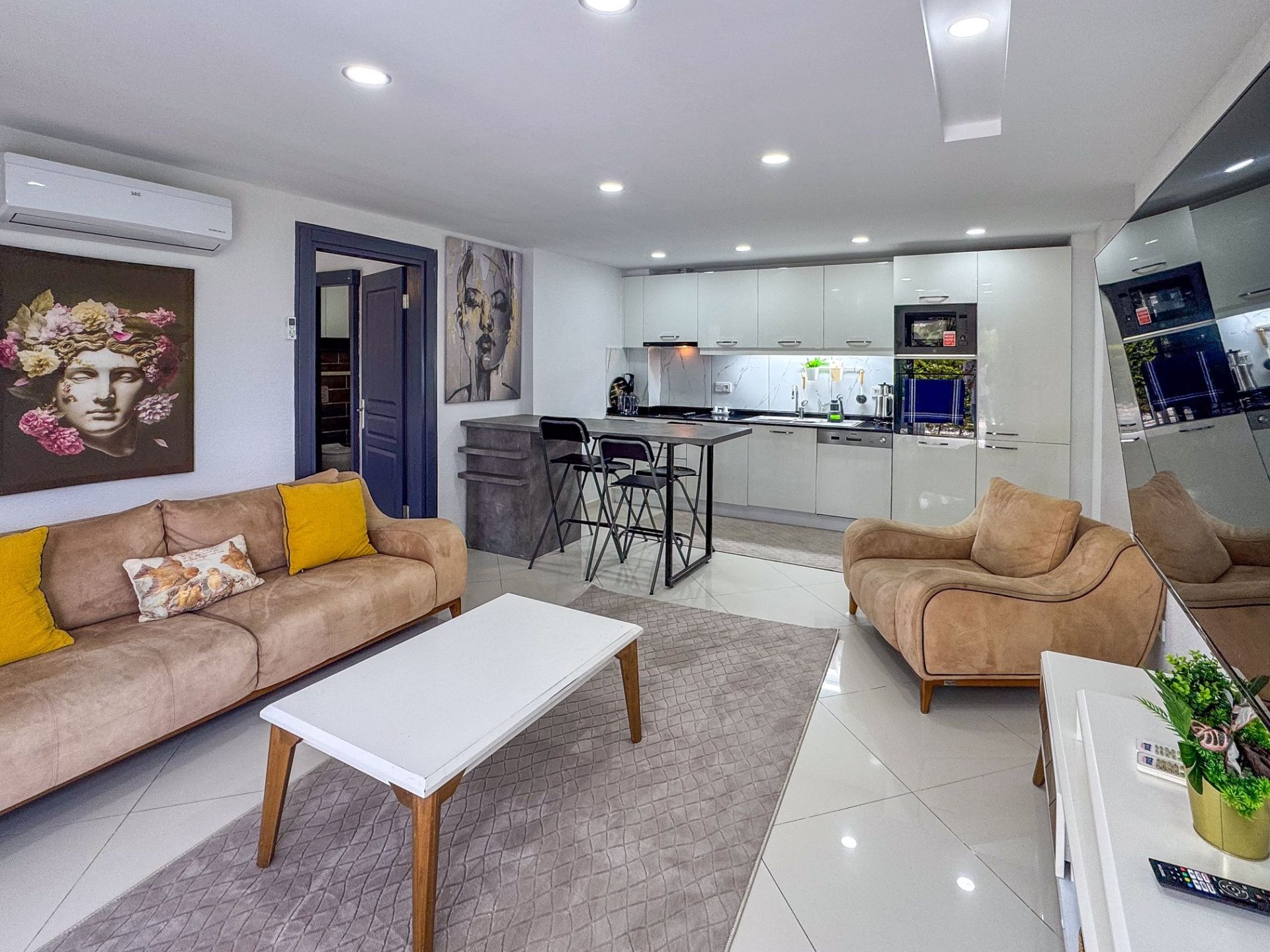 Open-plan living and dining area with breakfast bar leading into the modern white kitchen