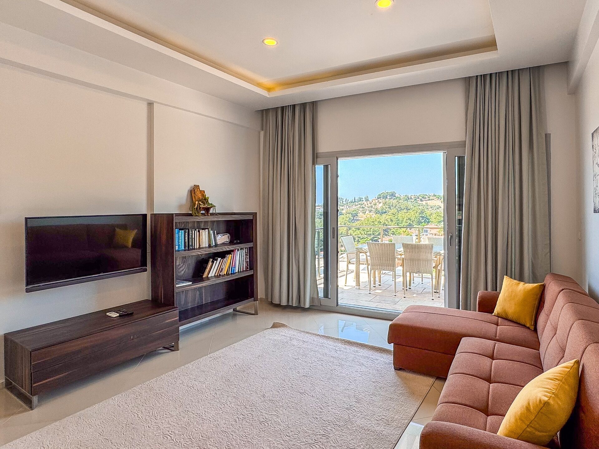 Bright penthouse living room with terracotta sofa and sliding doors onto the private terrace