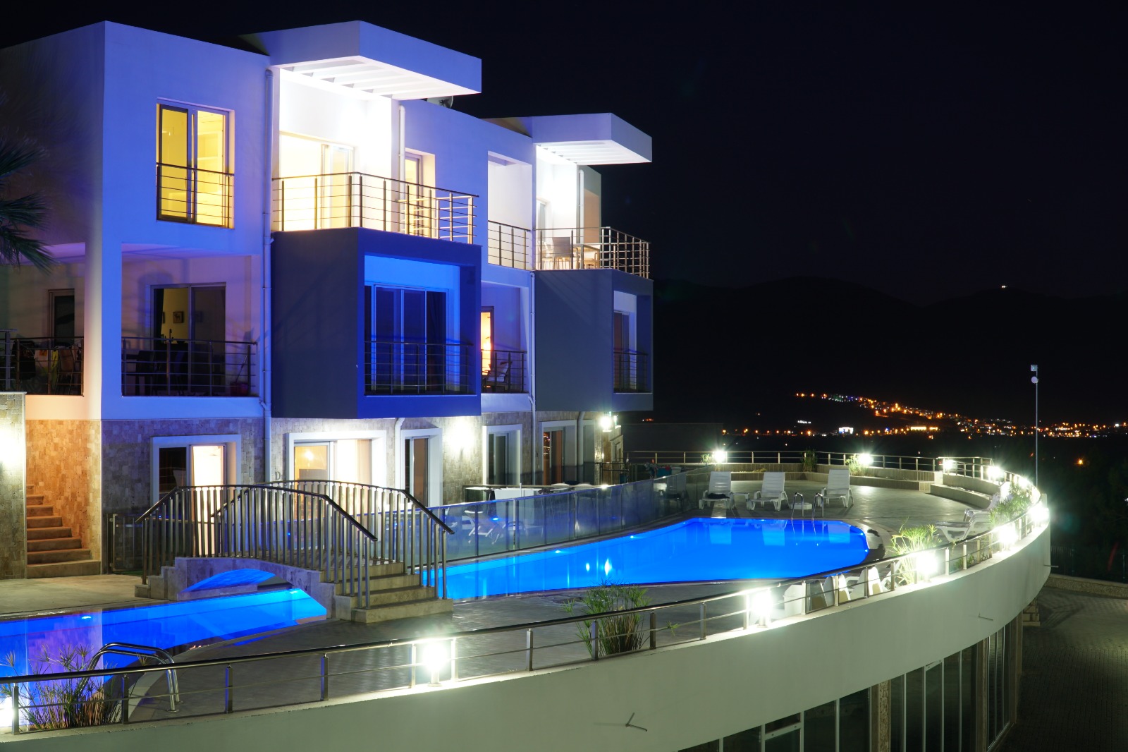 Lavender Residence pool, terrace and apartments glowing at night with valley lights beyond