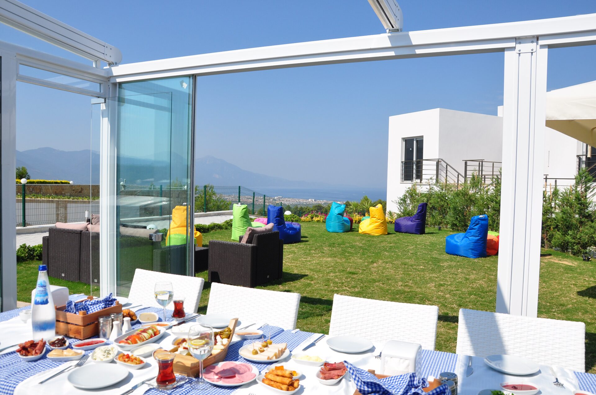 Turkish breakfast spread on a sea-view restaurant terrace with garden lounge beyond