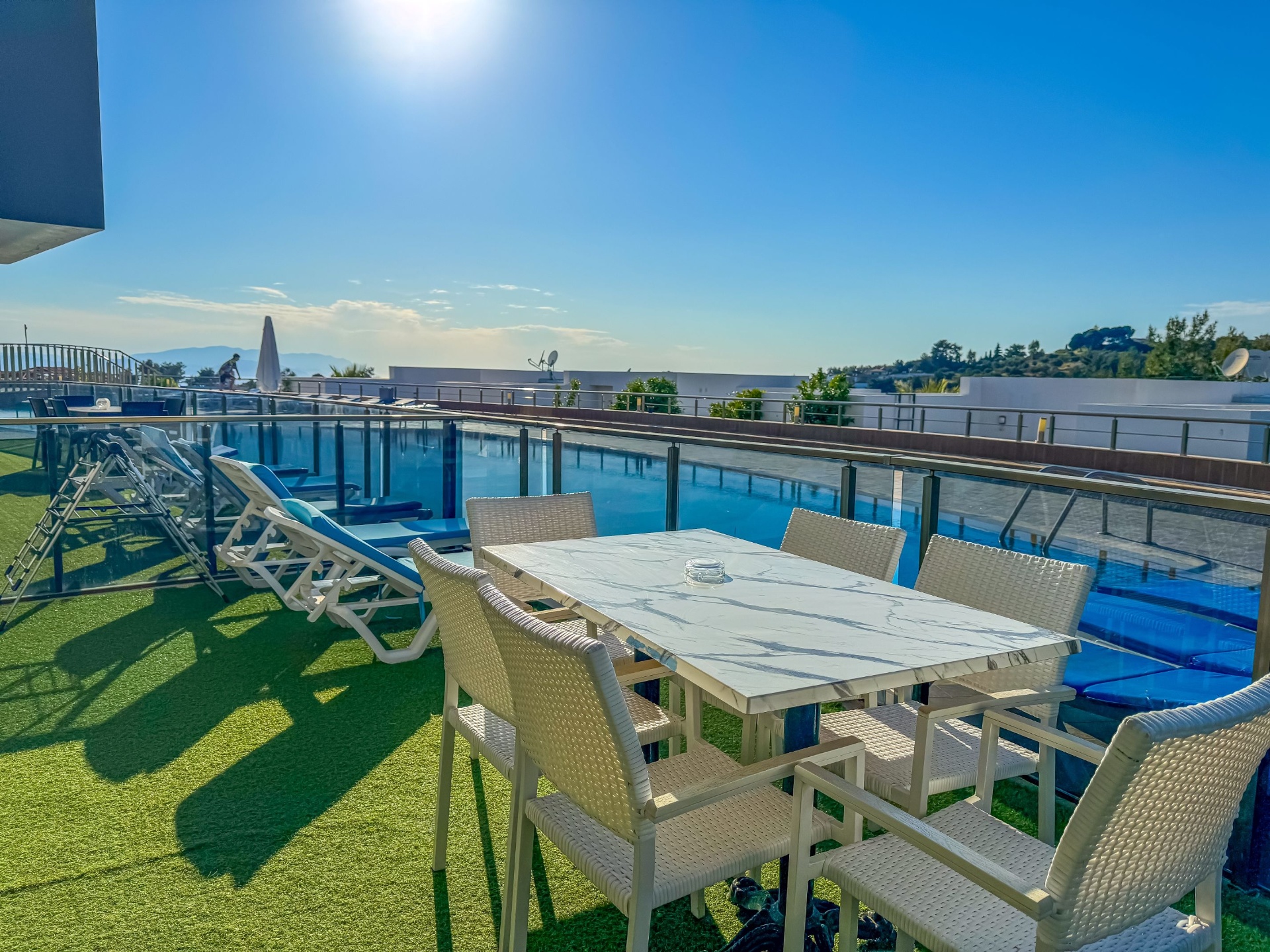 Pool-side terrace with dining table, sun loungers and Aegean horizon